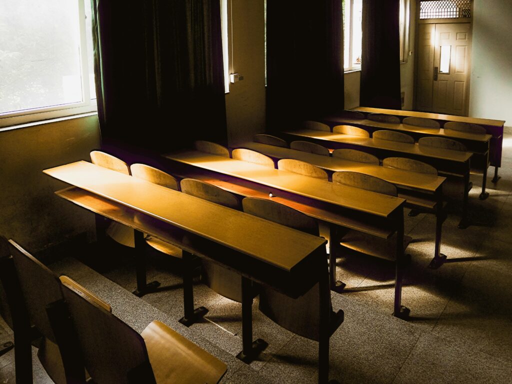 Sunlight streaming into an empty classroom with wooden desks and chairs in Hubei, China.